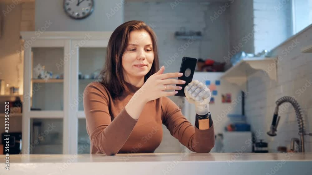 Handicapped woman holds a phone with a prosthesis, close up. Handicapped woman holds a phone with a prosthesis, close up.