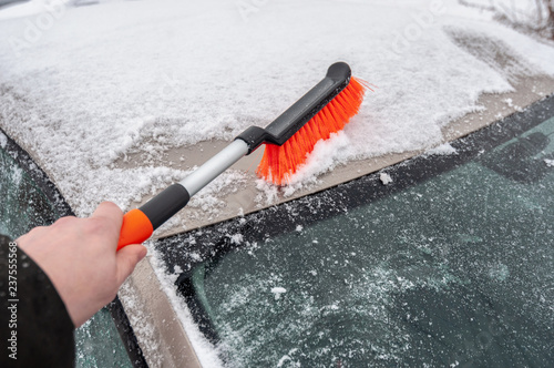 Removing snow from car windiow with a brush photo