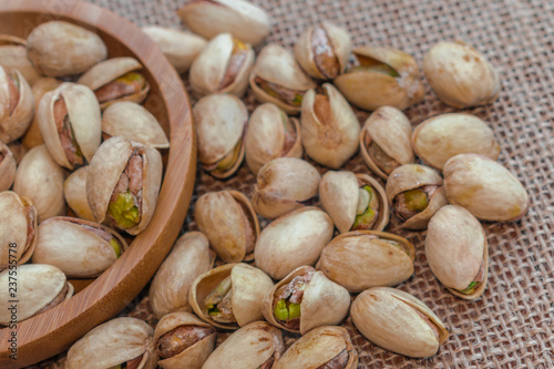 Pistachios in wooden bowl, and spilled on sack surface