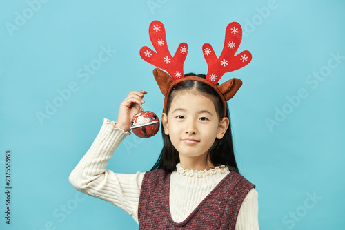 Asian girl with a Christmas concept headdress Child, Close up of cute little asian girl on blue background isolated.