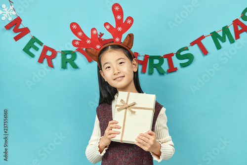 Asian girl with a Christmas concept headdress Child, Close up of cute little asian girl on blue background isolated.