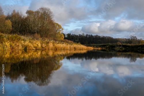 Autumn landscape with colorful trees and river. Reflection in river. © Roberts Ratuts