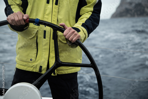  A sailing yacht skipper is at the helm. Close-up. It's cold, waves. photo
