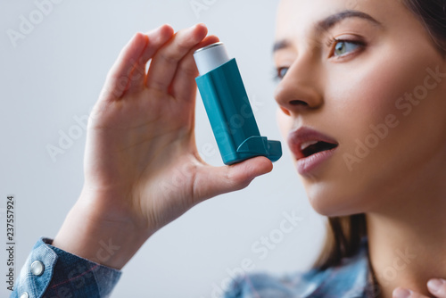 close-up view of young woman with asthma using inhaler photo