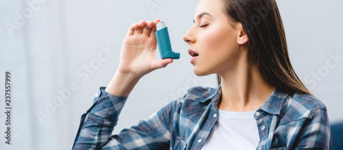 girl using inhaler while suffering from asthma at home photo