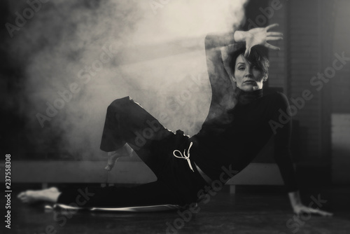 Photography modern beautiful dancer in black clothes posing against the Studio in the smoke