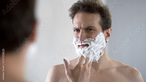 Slika na platnu Man preparing to shave, feeling discomfort and tingle on face from shaving foam