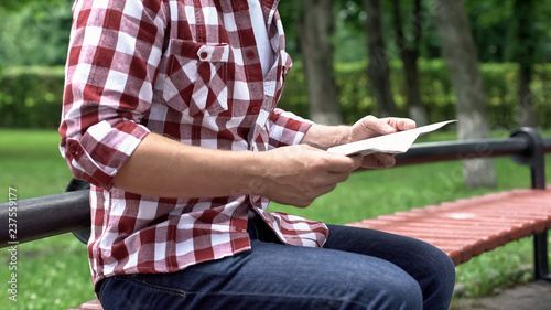 Casual man reading newspaper in park, spending leisure time, carefree weekend