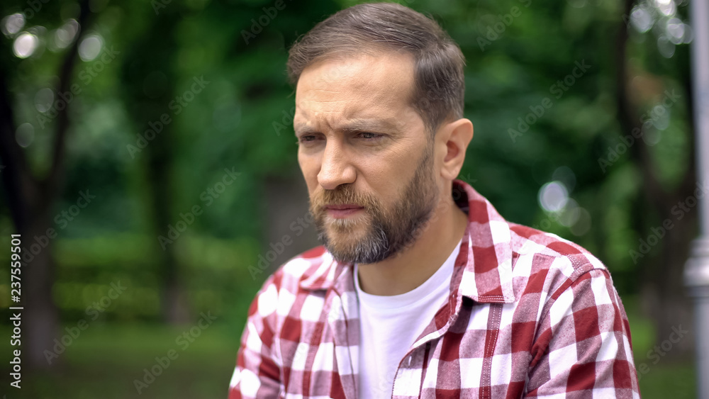 Troubled male sitting on bench in park, thinking of life difficulties, crisis Troubled male sitting on bench in park, thinking of life difficulties, crisis