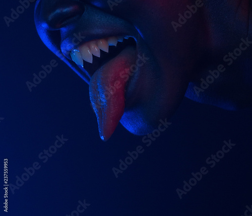 Female mouth with sharp fangs and bloody tongue. Halloween Horror night. photo