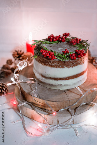 Christmas chocolate vanilla cake. Rustic homemade cake. Piece of cake. Vegan raw cake. Decorated rosemary and christmas tree. Lights and sparkler. Candle and garland on the background. 