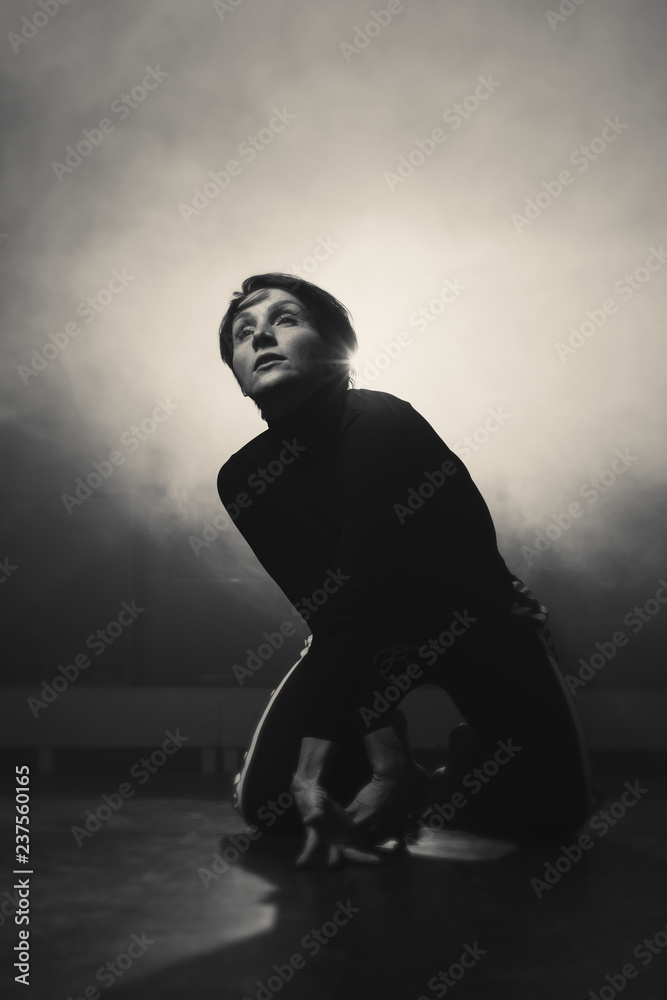 modern beautiful dancer in black clothes posing against the Studio in the smoke modern beautiful dancer in black clothes posing against the Studio in the smoke