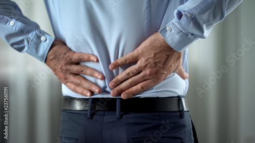Business person feeling lower back pain, nerves inflammation, kidneys disorder