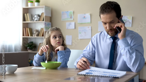 Foto Sad daughter looking at busy father ignoring her, lack of parental attention