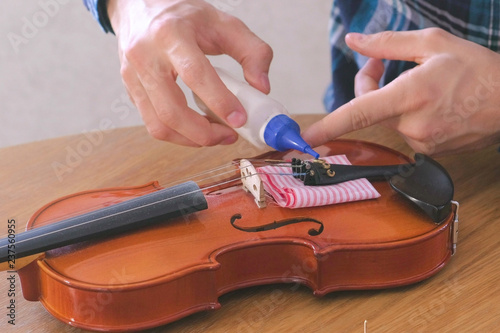Obraz na plátně Close-up hands of young man in plaid shirt is repairing a violin sitting at the table