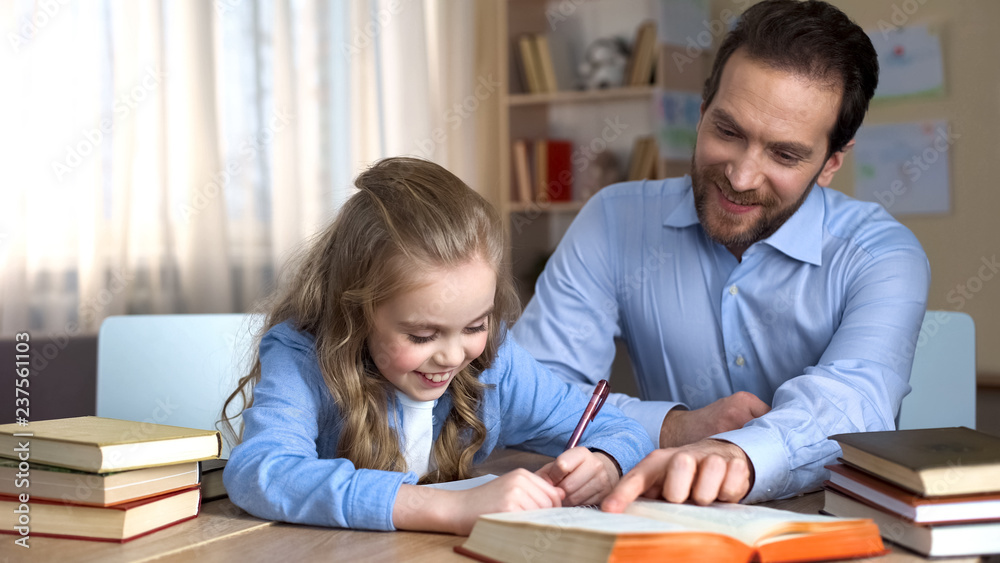 Smiling tutor helping little girl to learn new words, doing homework, education Smiling tutor helping little girl to learn new words, doing homework, education