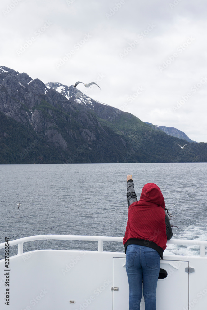 Scenic View of a Woman trying to touch a Seagull while  flying against Andes mountains, Nahuel Huapi National Park, Patagonia, Argentina