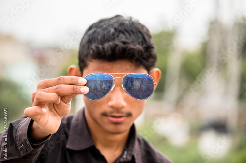 Young man holding sunglasses in front of his eyes
