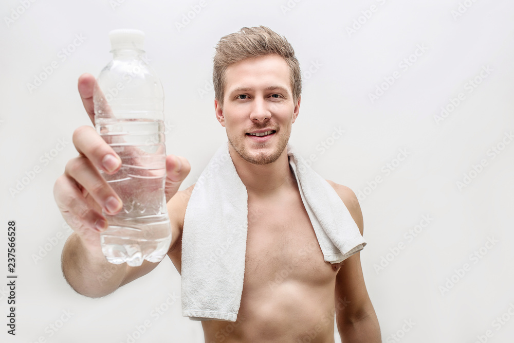 Handsome shirtless oyung man hold glass of water. He shows it on camera. Guy has towel around neck. Isolated on white background. Handsome shirtless oyung man hold glass of water. He shows it on camera. Guy has towel around neck. Isolated on white background.