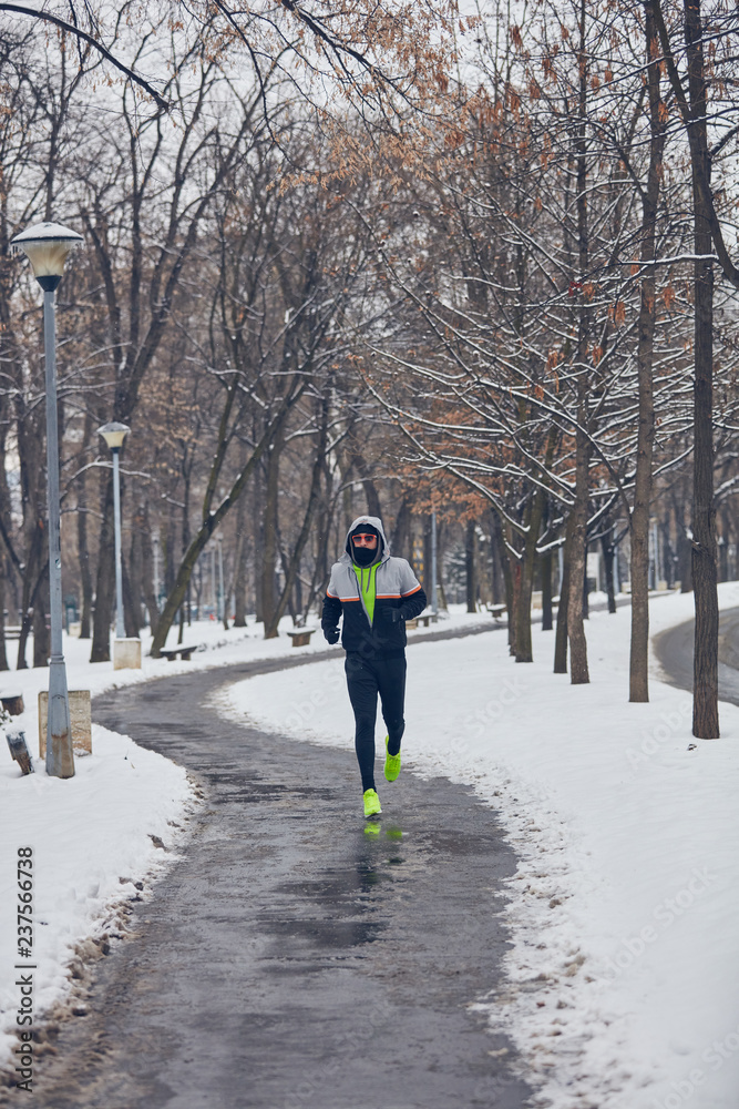 Man jogging in a cold winter snowy day outdoors.