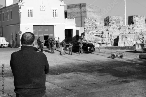 man watching the workers of the marina of Peniche in black and white