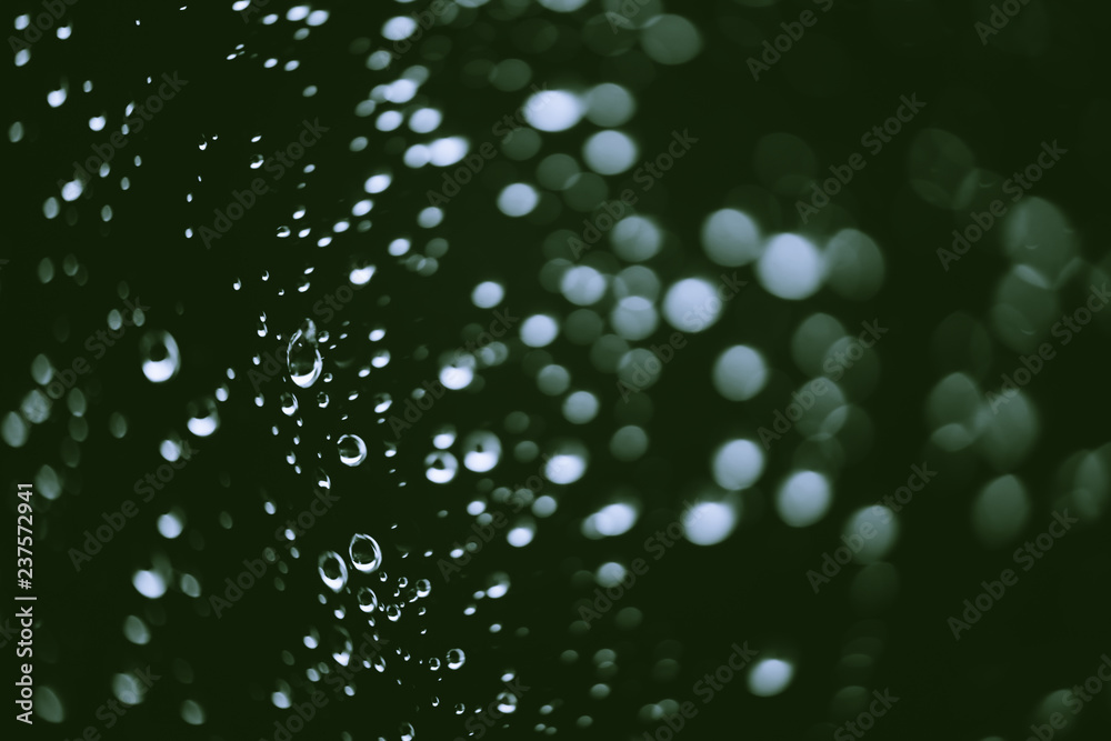 Dirty window glass with drops of rain. Atmospheric green background with raindrops in bokeh. Droplets and stains close up. Detailed transparent texture in macro with copy space. Rainy weather. Dirty window glass with drops of rain. Atmospheric green background with raindrops in bokeh. Droplets and stains close up. Detailed transparent texture in macro with copy space. Rainy weather.