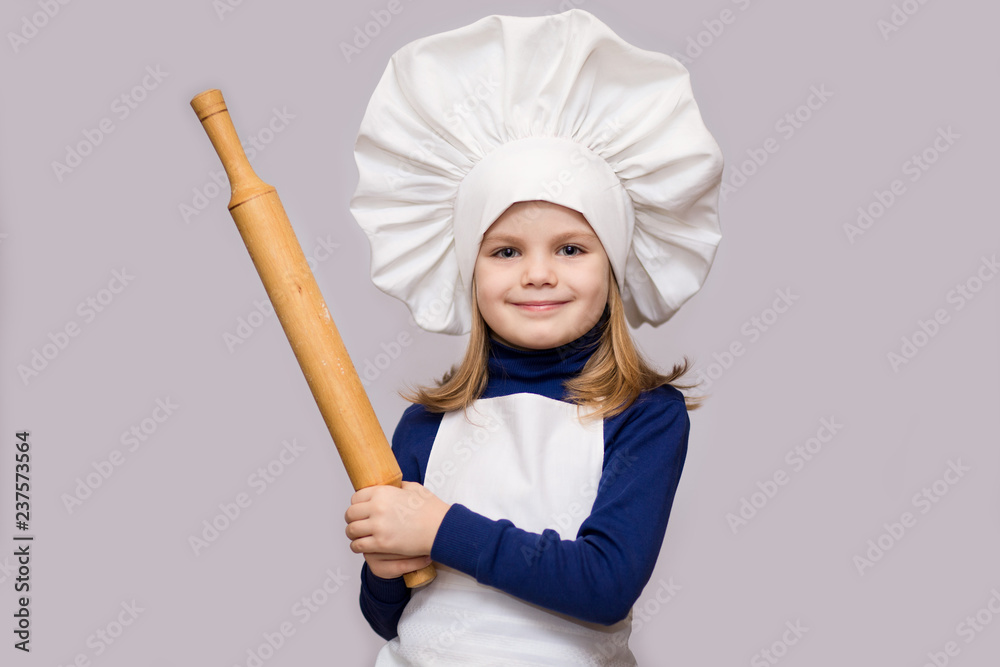 Children cook. Happy little girl in chef uniform holds rolling pin isolated on white background. Children cook. Happy little girl in chef uniform holds rolling pin isolated on white background.