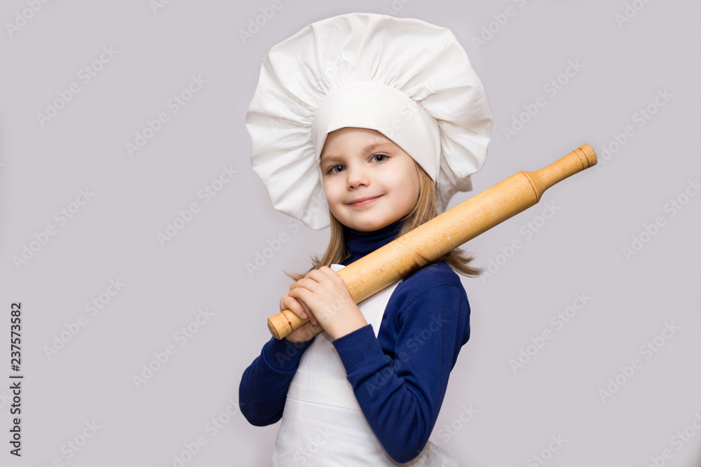Children cook. Happy little girl in chef uniform holds rolling pin isolated on white background. Children cook. Happy little girl in chef uniform holds rolling pin isolated on white background.