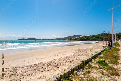 Right side of Bombas beach  with calm sea and hills and houses in the background  blue sky and clouds on the horizon  Bombinhas  Santa Catarina