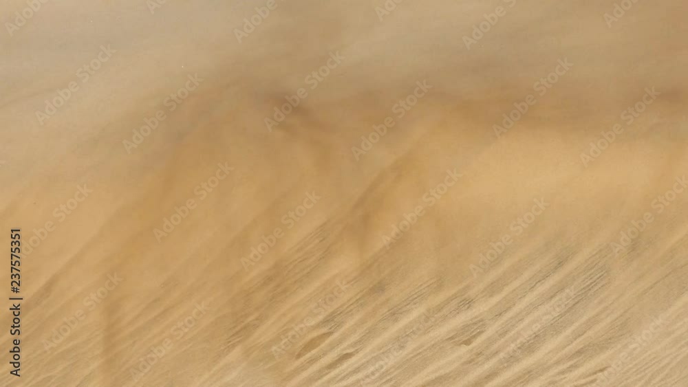 desert sand dunes with stormy winds and abstract sand movement and formations while the wind blows the grains and streaks in the air at playa ingles gran canaria spain