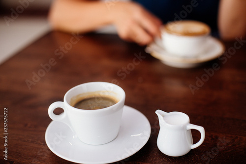 A cup of americano and milk separately.