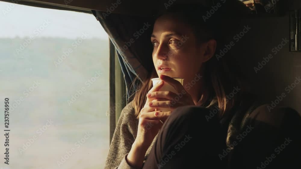 Young women drinking water while looking out of a asian train window