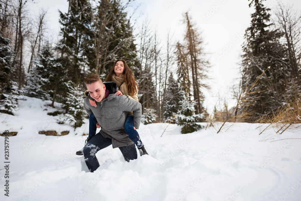 Fototapeta premium Happy man piggybacking woman in the snow