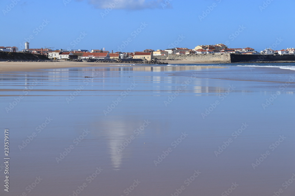 wet sand with city in background reflected
