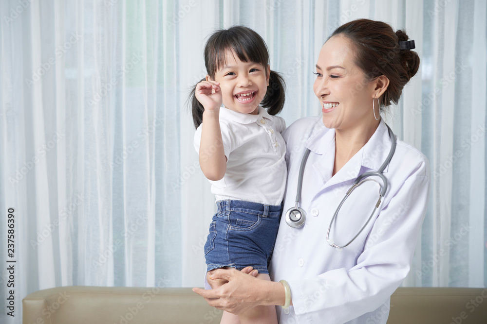 Mature Vietnamese pediatrician holding happy little Vietnamese girl Mature Vietnamese pediatrician holding happy little Vietnamese girl