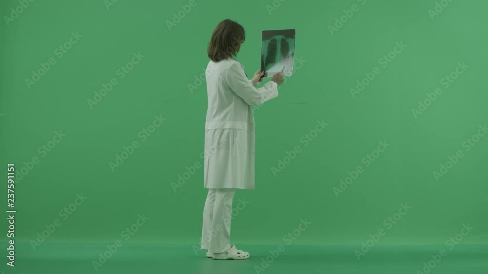 the doctor stands back side and explore the x-ray on green screen