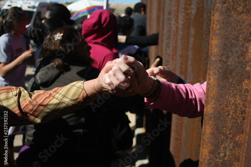 personas se saludan entre el muro que divide mexico de estados unidos photo