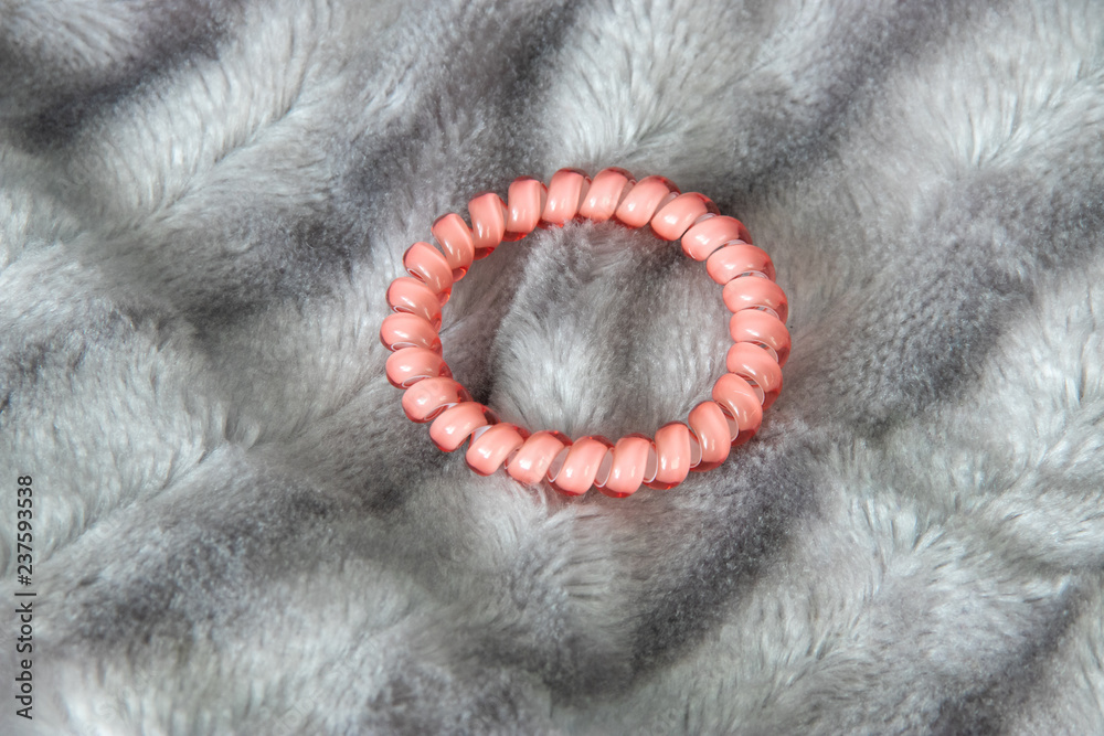 Obraz premium One pink scrunchy hair tie elastic spring on the silver gray fluffy faux fur blanket background