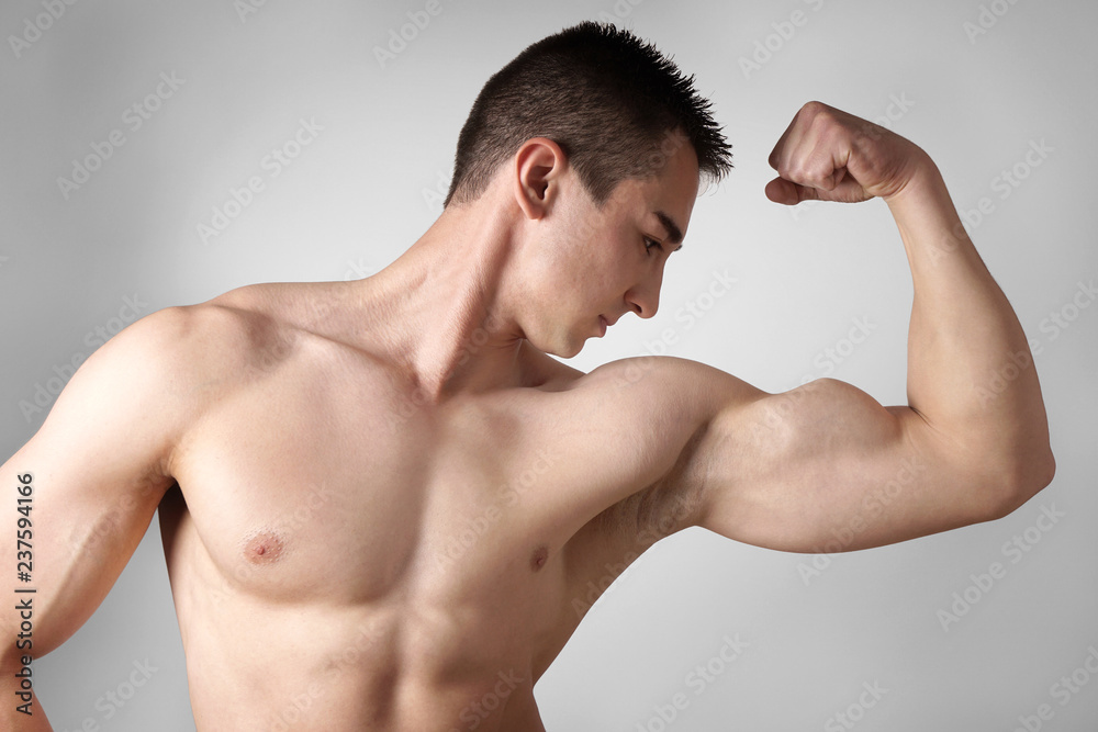 shirtless young man flexing biceps muscles showing strength Stock Photo