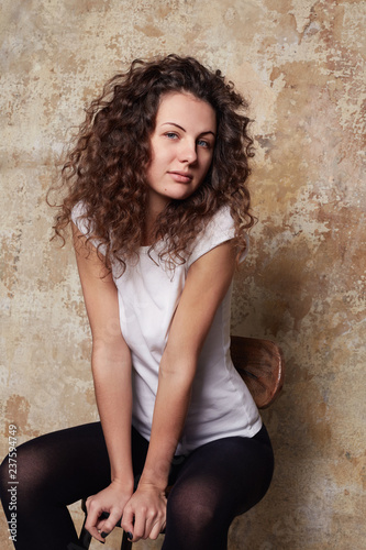 Young cute blue eyed seductive curly haired female posing for new season fashionable collection of women’s underwear, dressed in black tights and casual white cotton t-shirt. Advertisement concept. © Yulia