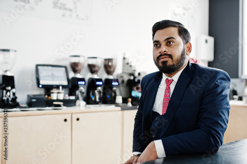 Stylish beard indian business man on suit sitting at cafe. photo