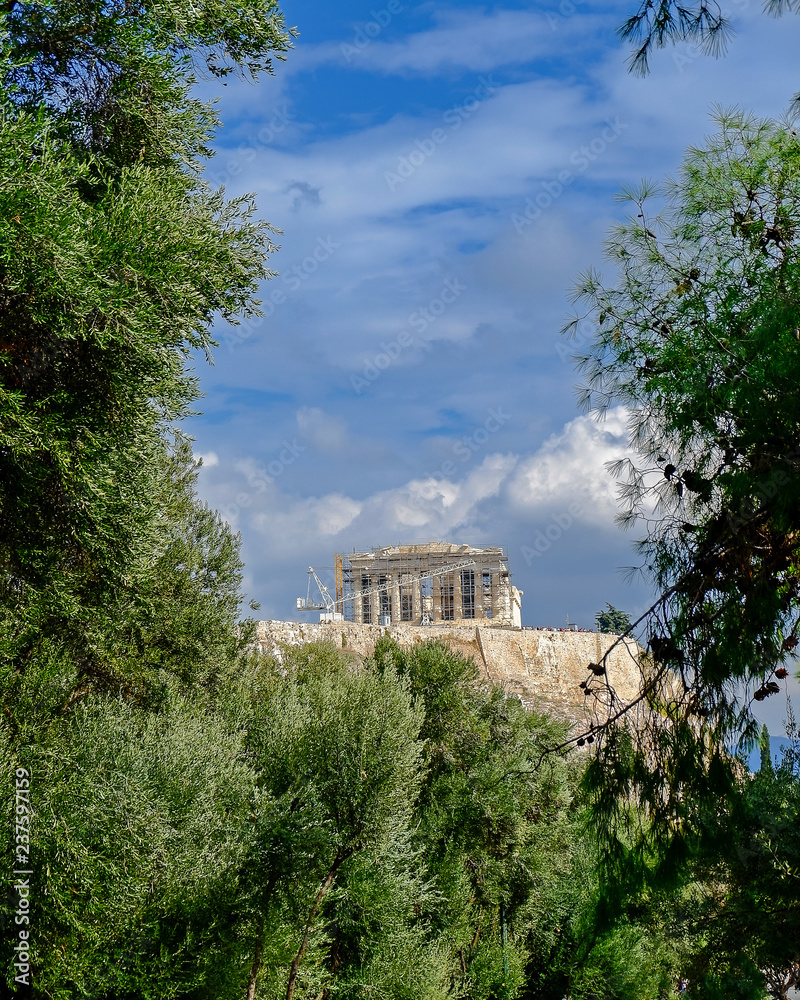 parthenon on acropolis hill between green folliage, Athens Greece