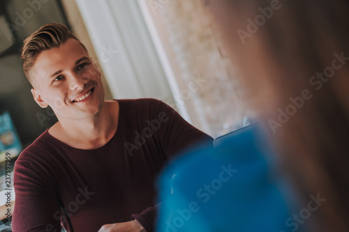 Concept of friendly atmosphere on meeting. Waist up selective focus on young cheerful man sitting in cafe with woman