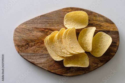 Bunch of salty crisps presented on a wooden board, grey background