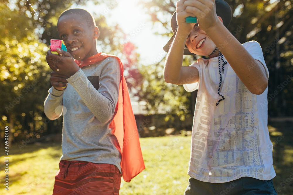 Obraz premium Kids playing with squirt guns outdoors