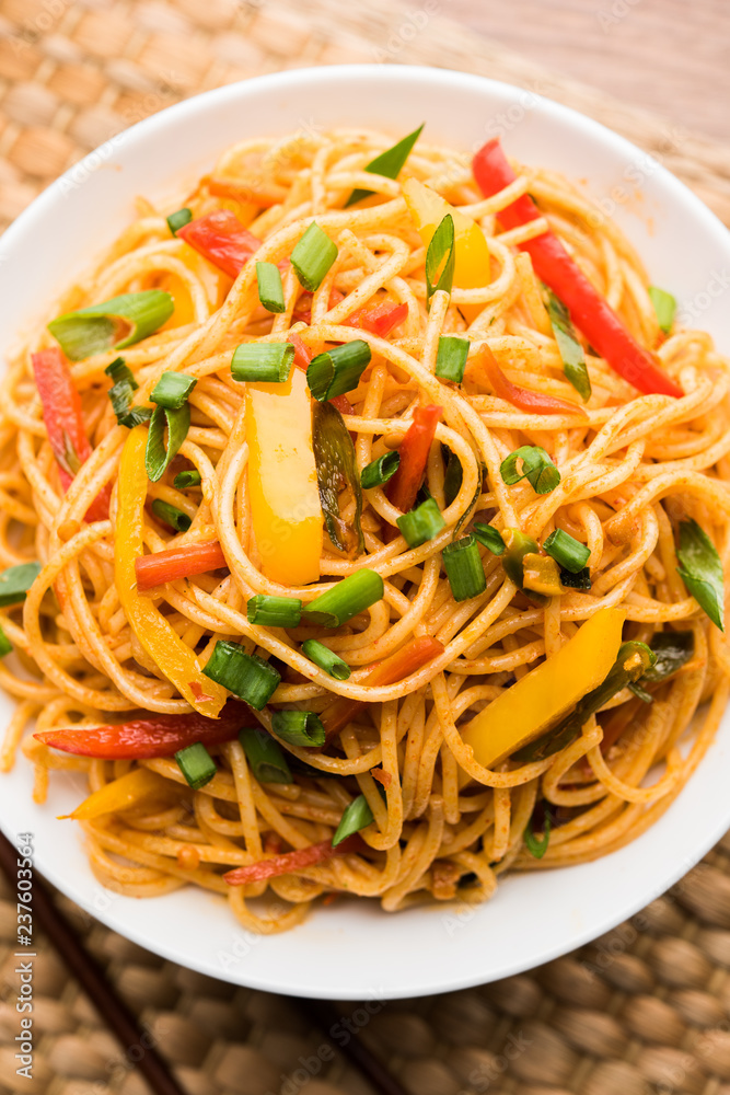 Schezwan Noodles or vegetable Hakka Noodles or chow mein is a popular Indo-Chinese recipes, served in a bowl or plate with wooden chopsticks. selective focus Schezwan Noodles or vegetable Hakka Noodles or chow mein is a popular Indo-Chinese recipes, served in a bowl or plate with wooden chopsticks. selective focus