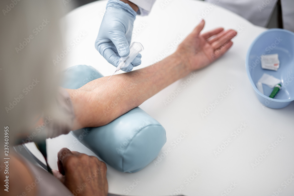 Obraz premium Professional doctor in rubber gloves using vacuum blood collection needle while working with patient