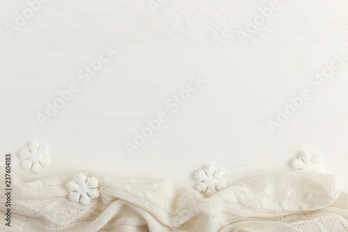 White snowflakes and knitted scarf on a wooden table. Christmas concept in bright colors. Copy space.