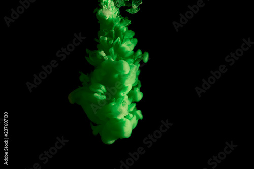 paint stream in water, colored ink cloud, abstract background, process of liquefaction green dye on a black background