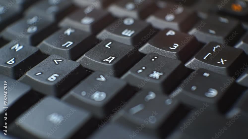 Black keyboard buttons with white Latin and Cyrillic letters slides in dark with blue backlight. Black keyboard buttons with white Latin and Cyrillic letters slides in dark with blue backlight.